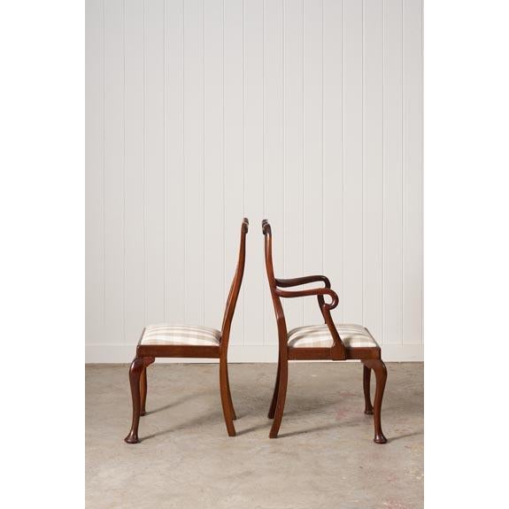 This set of eight 1930s walnut Queen Anne style dining chairs features cabriole legs with pad feet and turned stretchers....