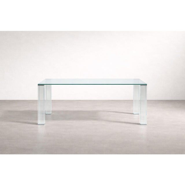 An elegant tempered glass table with a minimalist design, featuring clean lines and right angles with steel inserts. It...
