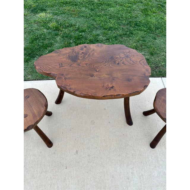 C. 1950s-60s mid-century rustic elm 3-piece table and stools set on tripodal legs. Table: 18.75"h x 32.5"w x 21"d Stools:...