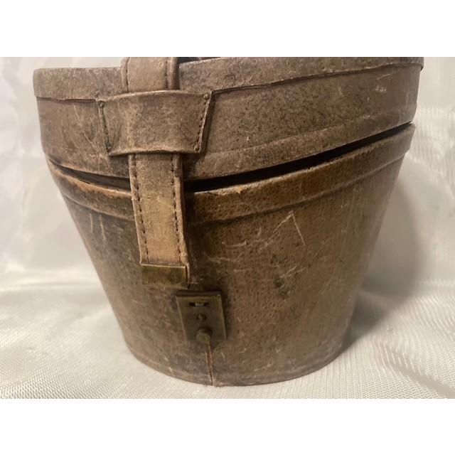 This is a striking late 19th-century antique Victorian leather top hat box case. It features a beautifully weathered,...