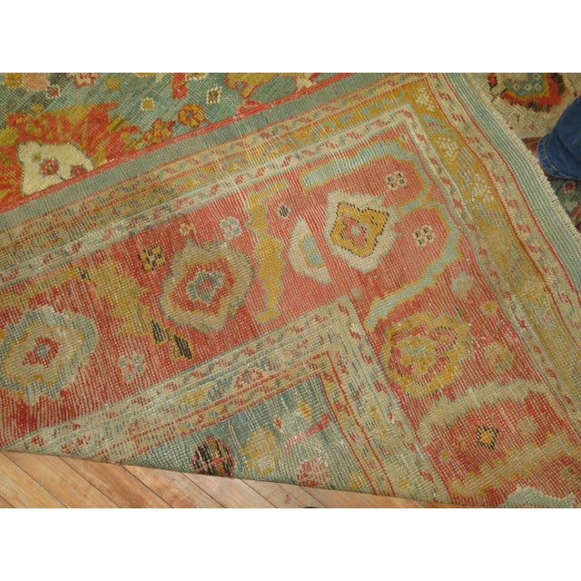 An exhilarating room size early 20th century antique turkish oushak rug with a vivid green field and orangy red border....