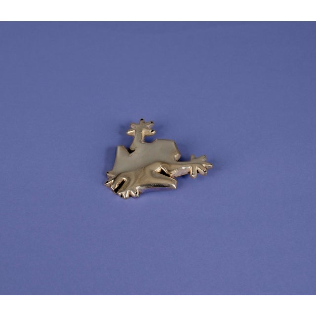 A handcrafted silver frog pendant with a clean, geometric design. This piece was made by a goldsmith and has a weight of...