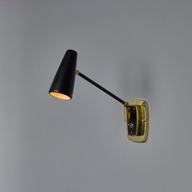 1950s Stilnovo Perforated Black Metal and Brass Sconce with Stamped Label Executed in brass and metal, these wall-mounted...