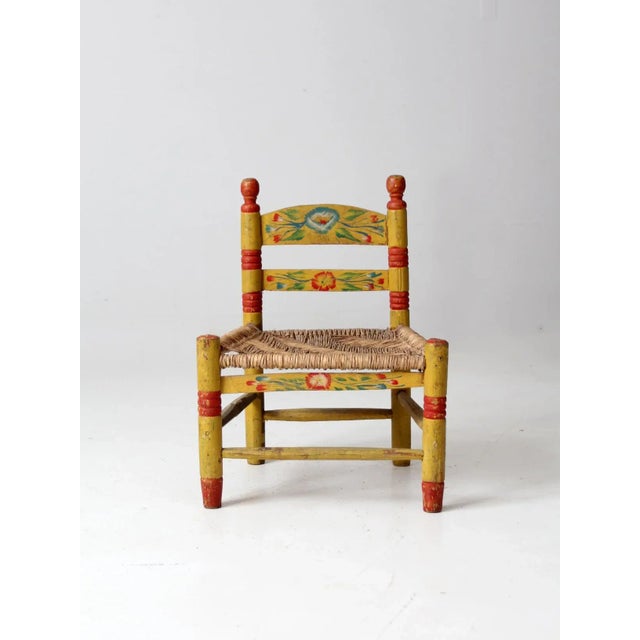 This is a vintage Mexican folk art children's chair. The bright, hand-painted chair has a floral theme with wooden frame...