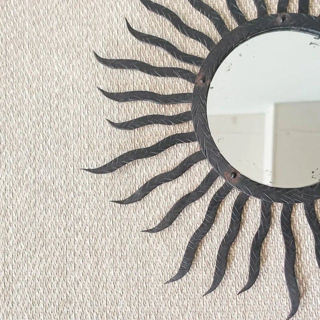 This sunburst mirror was designed and produced in Italy, during the 1950’s. It features a carved black metal frame made of...