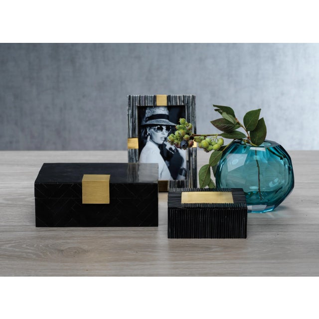 Elegantly designed in wood and resin with geometric design, and enhanced with polished brass accent, this box is just too...