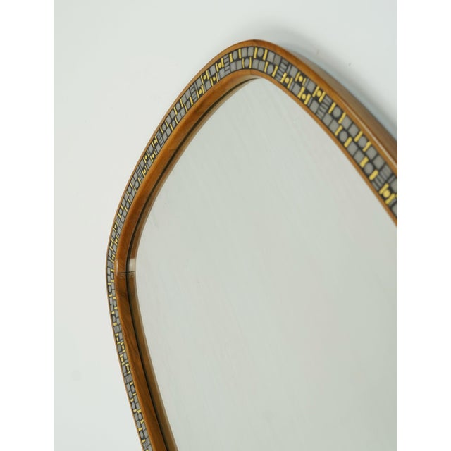 A beautiful and rare Mid-Century Modern wall mirror from the 1950s. The frame is made of solid cherry wood with a mosaic...