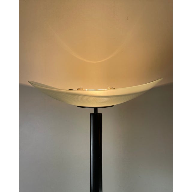Elegant floor lamp with an anthracite grey/black lacquered aluminum body and a half-moon-shaped shade of molded, frosted...
