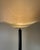 Elegant floor lamp with an anthracite grey/black lacquered aluminum body and a half-moon-shaped shade of molded, frosted...