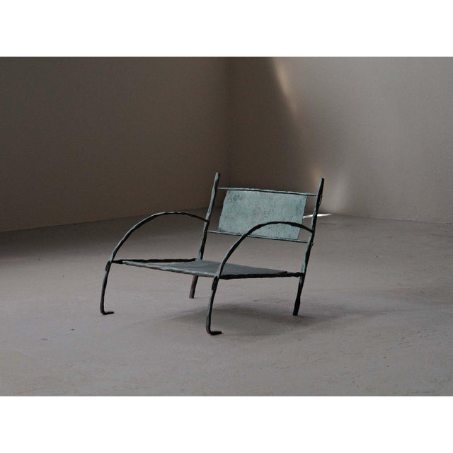 Low lounge chair, handcrafted in France around 1960, It is made from hammered wrought iron and folded steel sheet. Its...