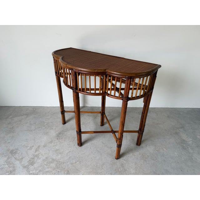 A beautifully crafted vintage demi-lune console table by Milling Road for Baker Furniture, featuring a rich bamboo frame...