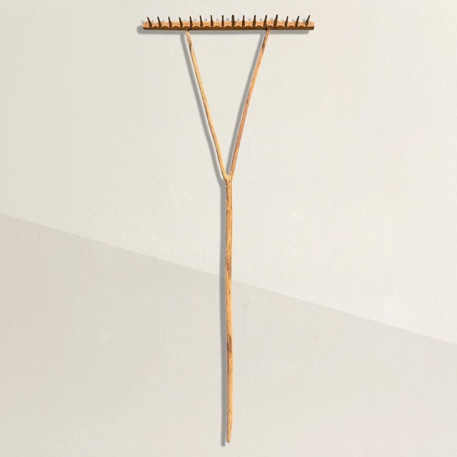 Originally a working tool, this late 19th-century garden rake has been reimagined as a sculptural wall piece. The handle,...