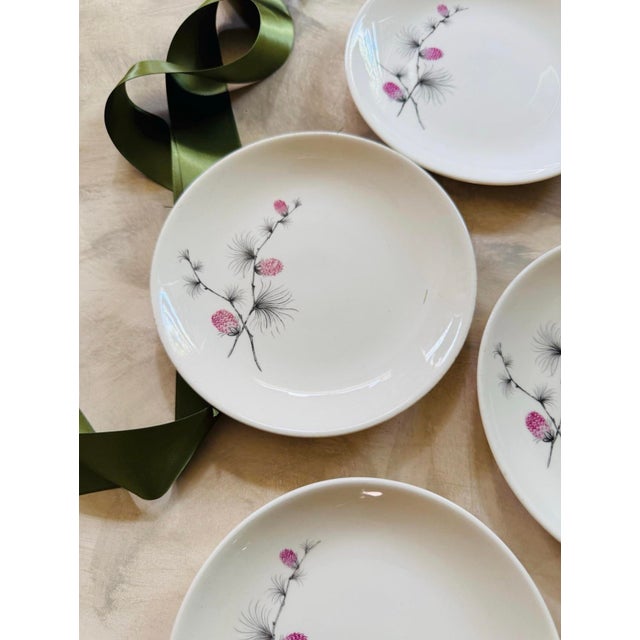 Lovely set of four vintage plates, presented on a soft white with a bright pink thistle flower on a black stem that bends...
