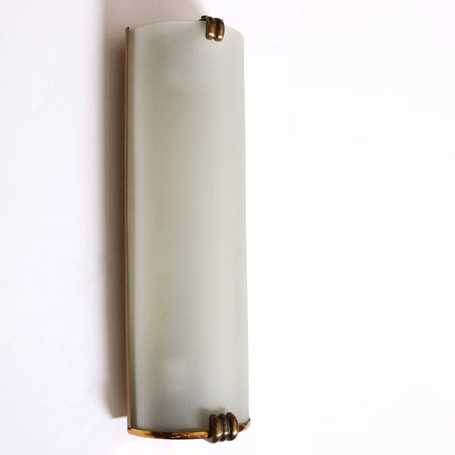 A beautiful single period Art Deco Sconce with stylized brass accents. Finely ribbed and frosted glass shades mounted on a...