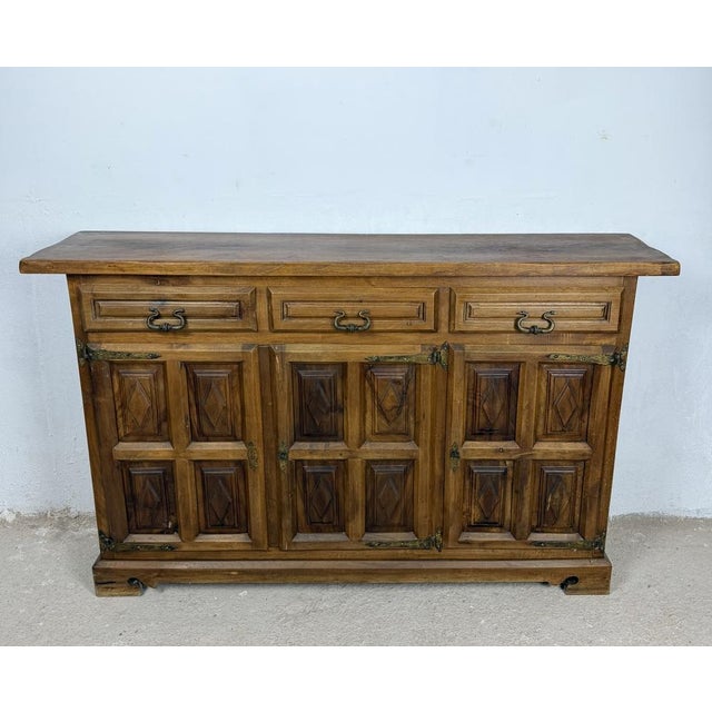 Beautiful Spanish sideboard crafted in solid walnut, featuring three upper drawers above three paneled cabinet doors with...