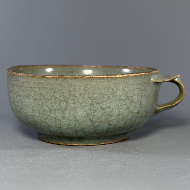 This antique Chinese Longquan celadon handled cup features beautiful crackle glaze all over the body. It has a single side...