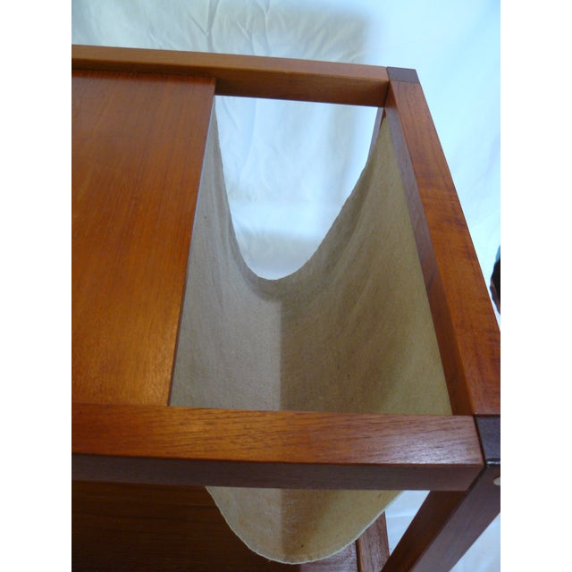 Very good used and vintage teak end table with integrated linen magazine sling and wheels. Appears to be mid-century...