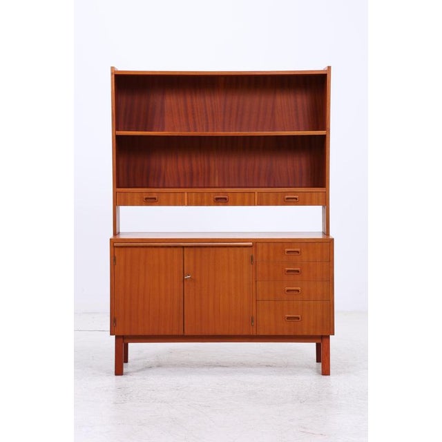 Vintage shelving unit with chest of drawers and hutch made of teak. The upper section offers three open compartments and...