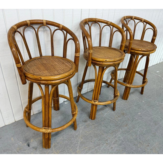 This listing is for a set of three Vintage Rattan Swivel Bar Stools. Featuring a rattan design, canned swivel seat, and...
