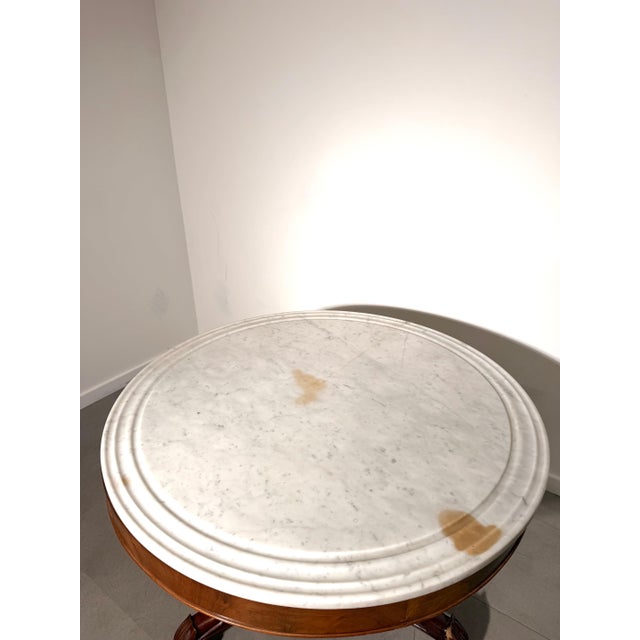 An elegant antique Victorian centre table featuring a beautifully carved solid mahogany pedestal base and a circular white...