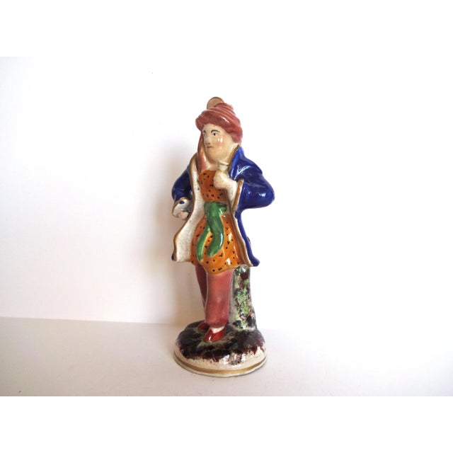 An antique Staffordshire figurine of a man dressed "a la turquoise" in a blue coat with a turban. Expected age crazing....