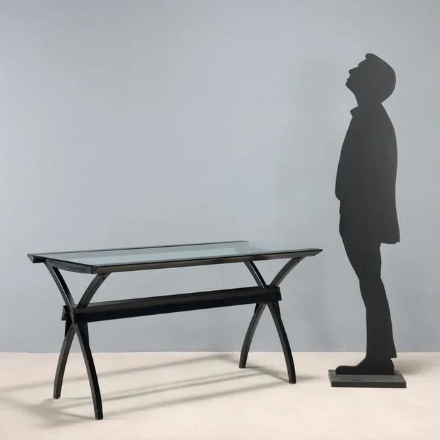 Desk with black lacquered wooden frame and rectangular glass top. This piece is attributed to the mentioned...