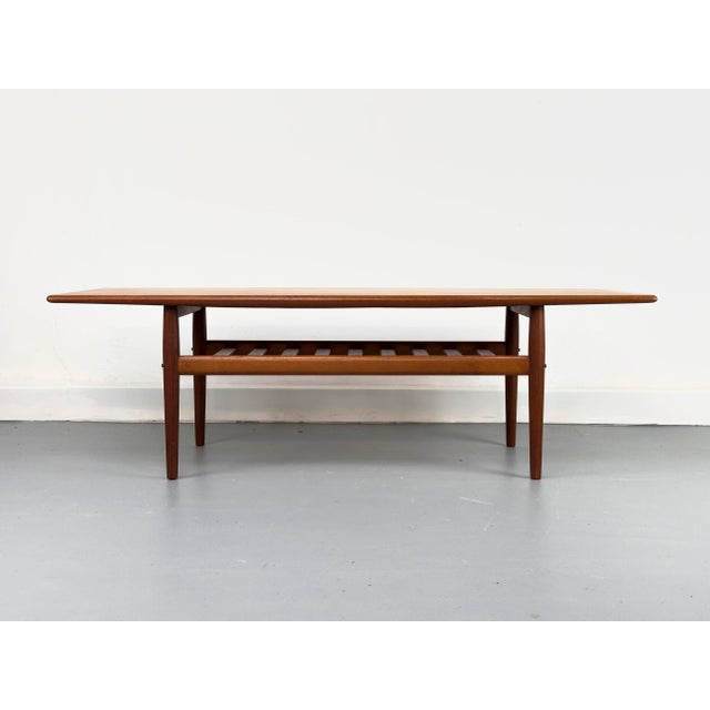 Iconic teak coffee table with an additional shelf beneath the main tabletop. Its distinctive features include the organic...