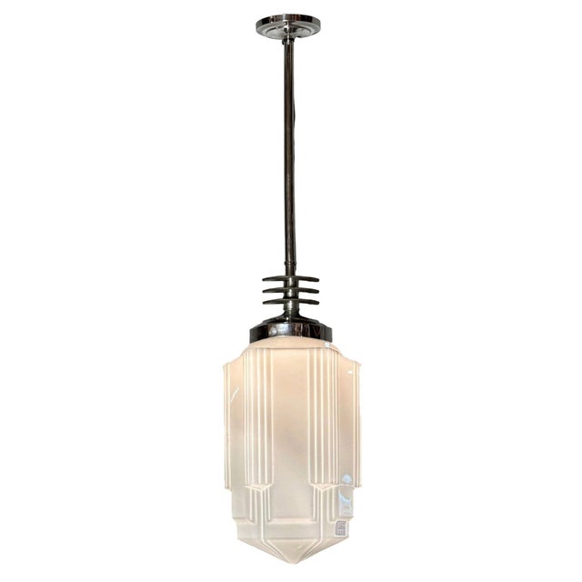 1930s Art Deco pendant light featuring a stepped and line-textured "Skyscraper" milk glass shade and Streamline Art Deco...