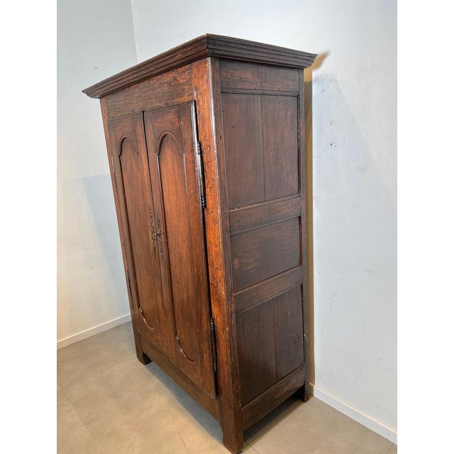 Authentic antique wardrobe in solid oak featuring beautifully shaped panel doors and original iron hardware. The cabinet...