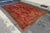 Design Plus Gallery presents a 9ft 2in x 14ft 2in Area Rug. The rug has a rustic red pattern with stylized motifs in rich...