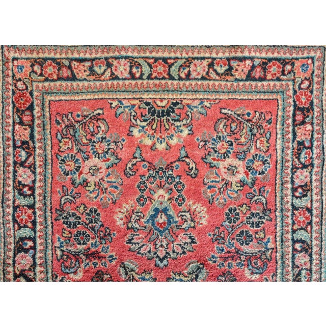 A wonderful early 20th century Persian Sarouk runner with a traditional all-over mirrored floral pattern woven in pink,...