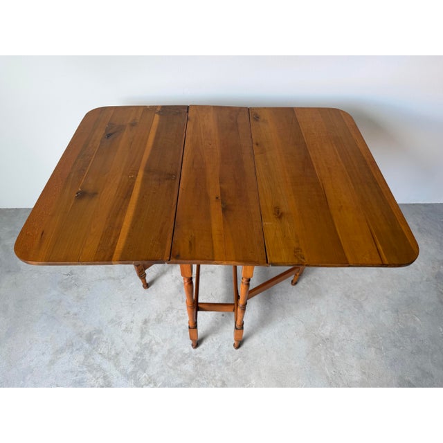 Beautiful and versatile, this vintage American drop-leaf dining table is crafted from solid cherry wood, showcasing warm...