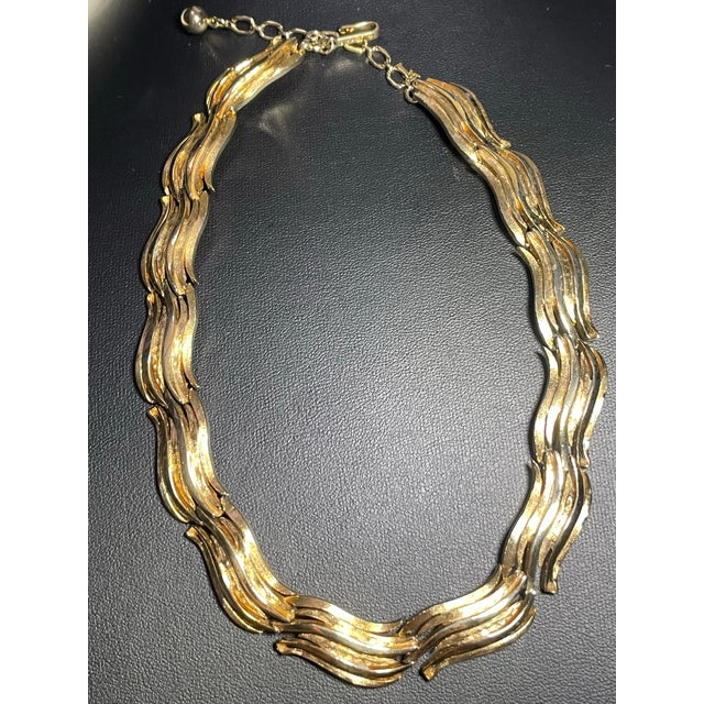This mid-century Crown Trifari choker necklace features flexible, articulated links composed of swept, flame-like ribbons...