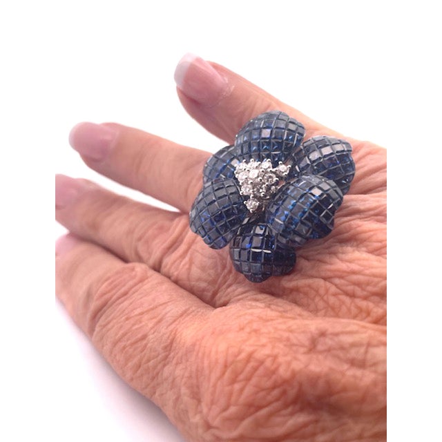 This huge Sapphire flower ring is set with invisible set Sapphire Stones. The center is set with Diamonds there are 10....