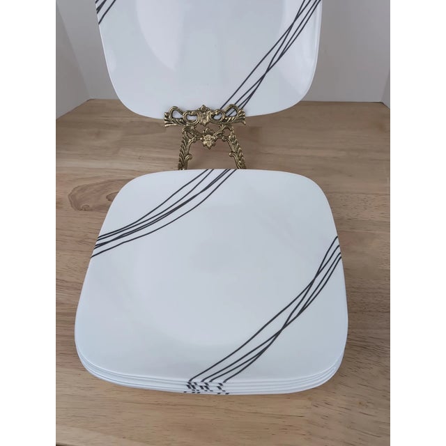 Classic vintage Corelle dinner plates in the Simple Lines pattern, featuring sleek black curved line accents on a crisp...