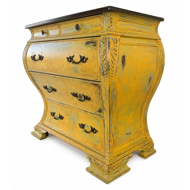 A striking vintage French Provincial bombe commode featuring an elegant serpentine form and hand-distressed mustard...