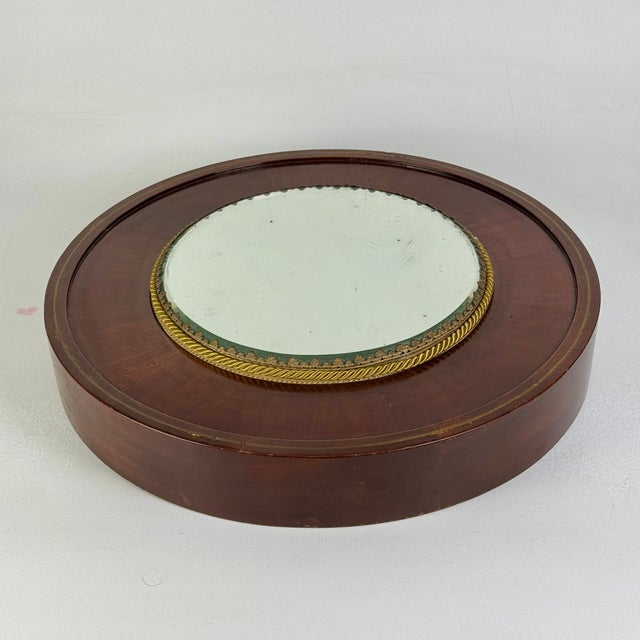 A gorgeous and unique antique rounded mirrored plateau gallery tray sitting atop a brass inlaid mahogany platform. This...