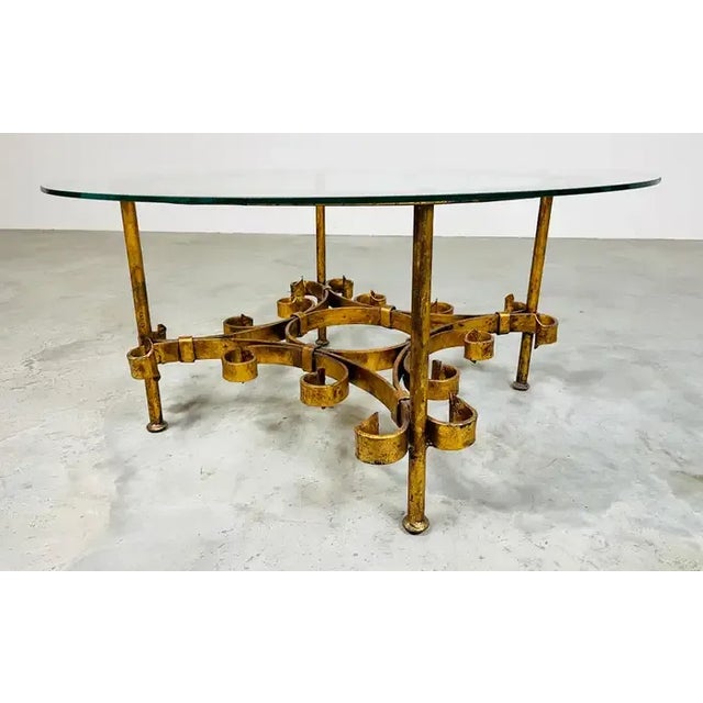 Hand forged iron parcel-gilt cocktail table with original 1/4" glass top designed in the manner of Gilbert Poillerat....