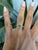 A rare demantoid garnet glows in a vivid, fiery green at the center of this solid 14K yellow gold ring, set in a floral...
