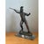 This vintage sculptural metal figure depicts a classical warrior in a dynamic, mid-action pose, one arm extended forward...