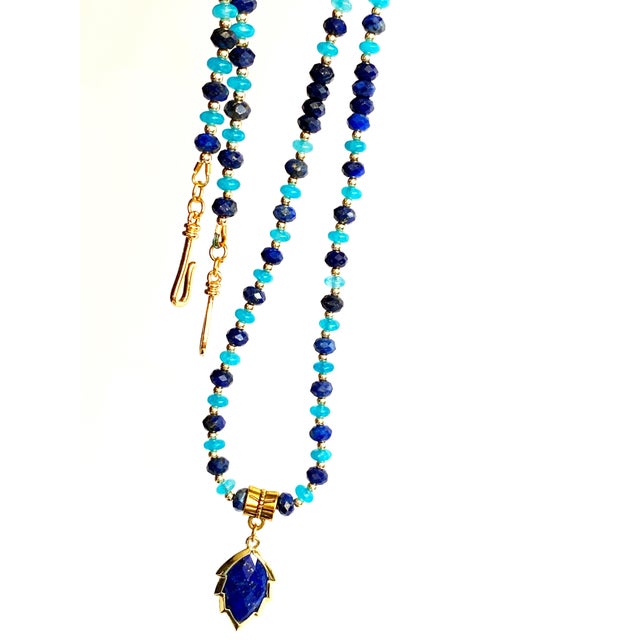 A striking composition of rich cobalt blues and luminous gold tones, this handcrafted necklace showcases a faceted Lapis...