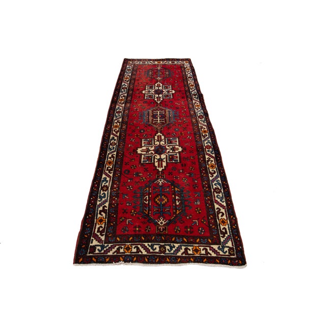 A stunning vintage Heriz handmade wool rug showcases a red field adorned with multicolored accents in a geometric all-over...