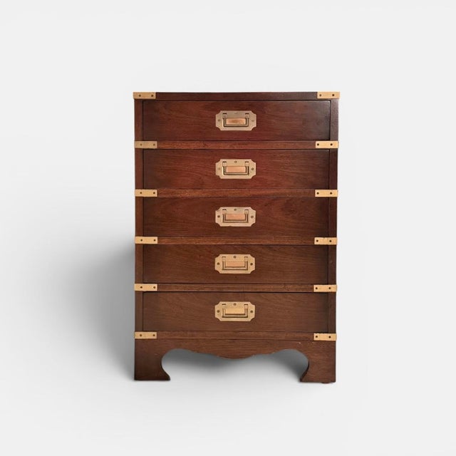 Chest of drawers executed in dark-stained wood with recessed brass handles and external brass corner fittings. inspired by...