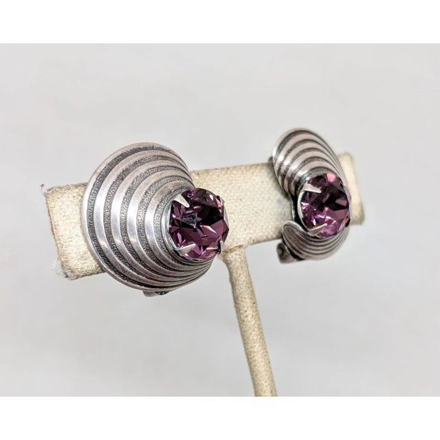 1950s Modernist silvertone ribbed half moon with round prong set faux-amethyst clip earrings. Marked "NAPIER PAT. PEND" on...