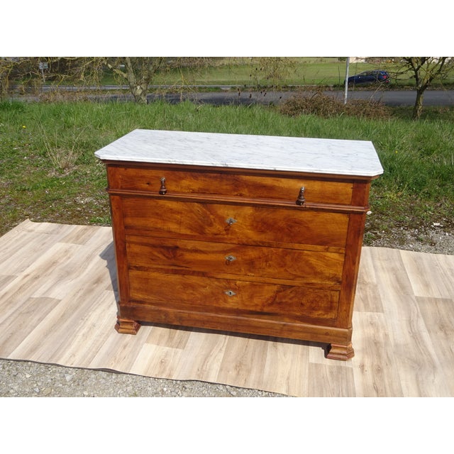 A Louis Philippe style chest of drawers with clean, simple lines, crafted from walnut with a Carrara marble top....