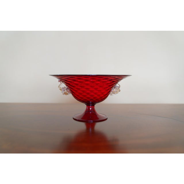 A striking vintage ruby red Murano art glass footed compote featuring a wide flared bowl, short pedestal base, and applied...