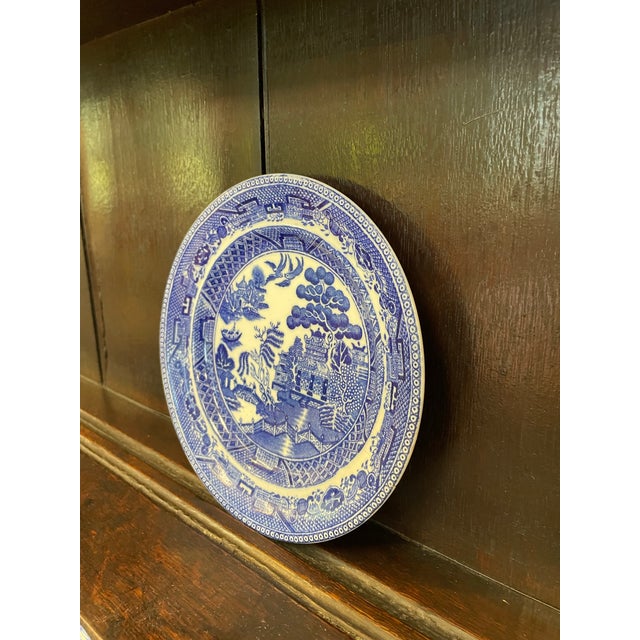A charming 19th-century English ironstone dessert plate featuring the iconic Blue Willow chinoiserie pattern in vivid...