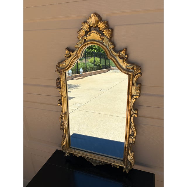 An elegant Italian giltwood mirror featuring a richly carved Rococo frame with scrolling acanthus details and original...