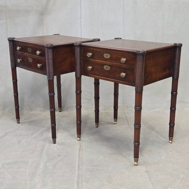An elegant pair of antique mahogany Federal style nightstands with distinctive circular carved porringer corners and...