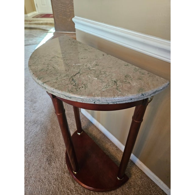 This demi-lune console table is a stunner! Italian marble with rich veining tops a neoclassical stand with gold accents on...